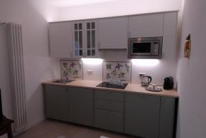 a kitchen with white cabinets and a sink and a microwave at Le Case di Elena - Gignese in Gignese