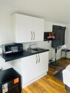 uma cozinha com um lavatório e um micro-ondas em Comfortable Annex em Orsett