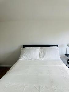 uma cama branca com lençóis brancos e uma cabeceira preta em Comfortable Annex em Orsett