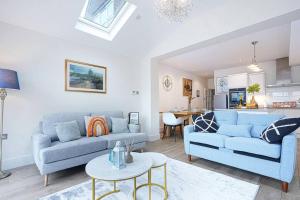 a living room with two blue couches and a kitchen at Beautiful House - Sleeps 8 - Close to City Centre with Free Parking, Fast Wifi and Smart TV with Virgin TV and Netflix by Yoko Property in Northampton