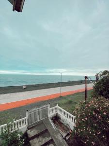 a white bench next to a beach with the ocean at Tbiliselebi Hotel Ureki in Ureki