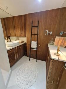 ein Badezimmer mit einem Waschbecken und einem Tisch mit einer Lampe in der Unterkunft Villa Gloria in Landaul