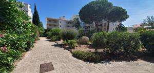 a brick pathway with bushes and trees and a building at Studio proche plage tout à pied in Fréjus