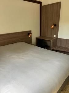 sypialnia z białym łóżkiem i drewnianym zagłówkiem w obiekcie Relais des Ardides w mieście Bonnemazon +2 zdjęcia