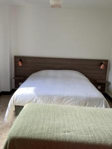 a bedroom with a white bed with a wooden headboard at Relais des Ardides in Bonnemazon