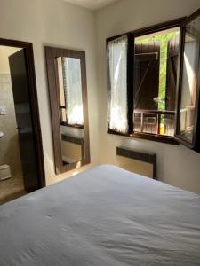 a bedroom with a white bed and two windows at Relais des Ardides in Bonnemazon