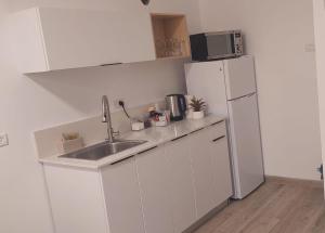 a white kitchen with a sink and a refrigerator at יחידת אירוח אור בזלת in Qiryat Shemona +4 photos