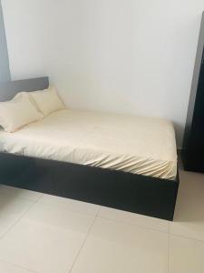 uma pequena cama com uma moldura preta e lençóis brancos em Rahims 3 Bed Bungalow - Dalaba em Jarbang