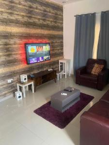 a living room with a couch and a tv at Rahims 3 Bed Bungalow - Dalaba in Jarbang