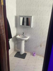 uma casa de banho com um lavatório branco e um espelho. em Rahims 3 Bed Bungalow - Dalaba em Jarbang