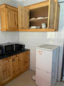 a kitchen with a white refrigerator and wooden cabinets at Rahims 3 Bed Bungalow - Dalaba in Jarbang