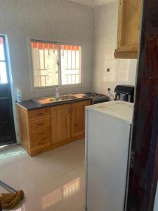 uma cozinha com um frigorífico branco e armários de madeira em Rahims 3 Bed Bungalow - Dalaba em Jarbang