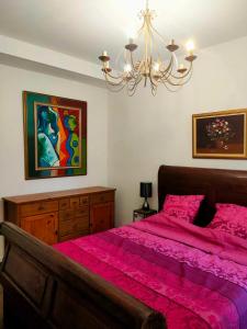 Un dormitorio con una cama con sábanas rosas y una lámpara de araña. en Unique, central et calme, en Niza
