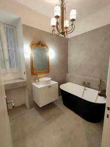 een badkamer met een bad, een wastafel en een spiegel bij Unique, central et calme in Nice
