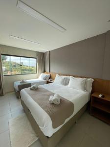 a bedroom with two beds and a large window at VIVER Pousada Club & Restaurante in Saquarema