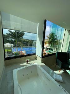 a bath tub in a bathroom with a view of a pool at VIVER Pousada Club & Restaurante in Saquarema