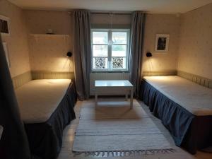 um quarto com duas camas com uma mesa e uma janela em Trevligt eget hus med kakelugn i lantlig miljö em Vikingstad