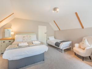 a bedroom with two beds and a chair in it at The Glebe in Heckington
