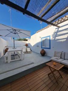 eine Terrasse mit einem Sofa, einem Tisch und einem Sonnenschirm in der Unterkunft Casa de Santa Margarida in Mourão