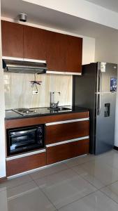 a kitchen with wooden cabinets and a stove and a refrigerator at Departamento 2 ambientes full amenities + Cochera in Santa Cruz de la Sierra