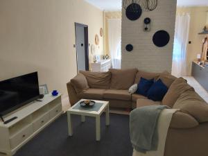 a living room with a couch and a tv at Türkiz Apartman - 5 szobás 13 fős apartmanház 4km a Balaton- Balatonszabadi in Balatonszabadi