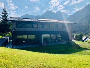 una casa en una colina con montañas en el fondo en Kracha Alpinlodge en Mittelberg