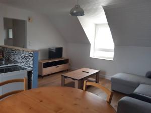 sala de estar con mesa de madera y cocina en Agréable petit T3, à proximité de Quimper, en Ergué-Gabéric