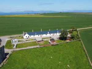 an aerial view of a white barn in a field at Grieves Cottage in Portmahomack