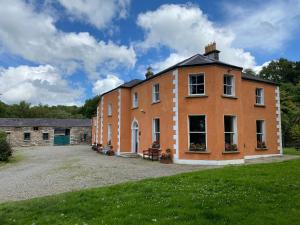 ein großes orangefarbenes Backsteingebäude mit einem Rasenplatz in der Unterkunft Clone Country House in Aughrim