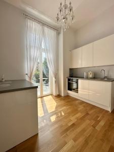 uma cozinha com armários brancos e uma grande janela em Apartament MARILYN w Kamienicy Wicherkiewiczów em Poznań