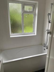 a white bath tub in a bathroom with a window at Hallykins in Erith