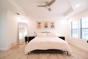 a white bedroom with a bed and a ceiling fan at The Sleepy Owl in Plano