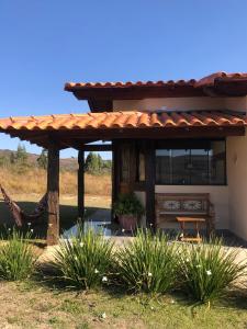 une pergola en bois sur une maison ornée de plantes dans l'établissement Chalés para temporada - Chalés Apuã - 500 metros da Cachoeira, à Carrancas