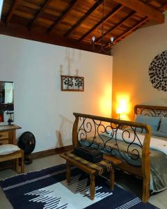 um quarto com uma cama, um banco e um candeeiro em Chalés para temporada - Chalés Apuã - 500 metros da Cachoeira em Carrancas