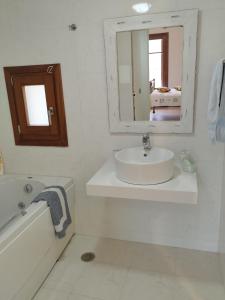 a bathroom with a sink and a mirror and a tub at Lovers' Nest in Mesariá