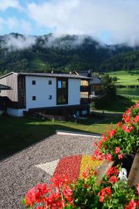 ein Haus in den Bergen mit Blumen im Vordergrund in der Unterkunft See Hotel Kärntnerhof- das Seehotel am Weissensee! in Weissensee