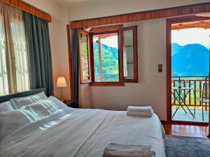 Schlafzimmer mit einem Bett und Fenstern mit Aussicht in der Unterkunft Majestic Vista Residence in Metsovo