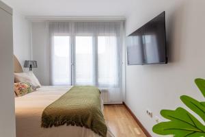 1 dormitorio con 1 cama y TV en la pared en Delux3Rooms by Asturias Holidays, en Gijón
