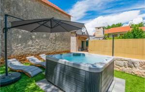 a hot tub with an umbrella in a yard at Cozy Home In Gornji Vinjani With Wifi in Gornji Vinjani