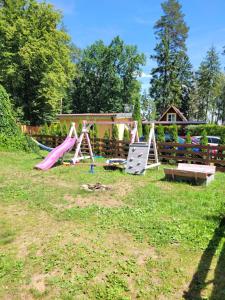 um quintal com um parque infantil com um escorrega em Domek Drewniany w Dolinie Symsarny em Lidzbark Warminski