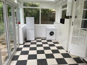 a kitchen with a washing machine and a checkered floor at Hallykins in Erith