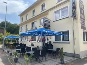 ein Restaurant mit Tischen, Stühlen und blauen Sonnenschirmen in der Unterkunft Hotel Am Wildpark in Sankt Ingbert