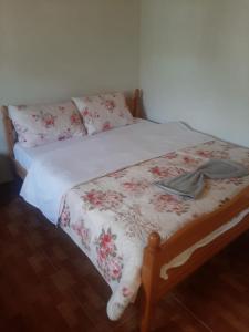 a bed with a white bedspread with flowers on it at Guesthouse Zvina in Pukë