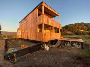 a wooden house sitting on top of a field at Buchuvillas Surf House in Buchupureo +16 photos