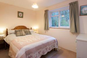 a bedroom with a bed and a window at Watermill Cottages - 18th Century converted Mill 10 mins from beach in Dartmouth