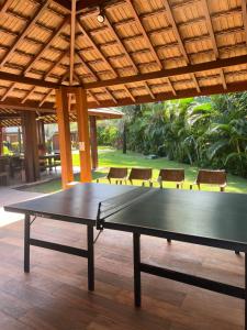 a ping pong table sitting under a pavilion with chairs at Apartamento 2 suítes em condomínio de luxo no centro in Praia do Forte