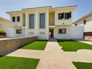 uma casa com um relvado verde em frente em Fabulous beach front house with pool em Lárnaca