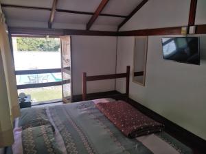 謝內吉亞區的住宿－Casa de campo en Cieneguilla con Piscina，一间卧室设有一张床、一台电视和一个窗口。
