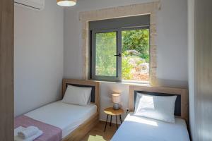 two beds in a room with a window at Aerino in Chania Town