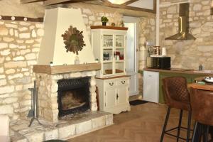 a kitchen with a fireplace in a stone wall at Maisonnette du bonheur - Vue campagne - Baignoire Balnéo 32 jets - Lits Queen size in Vadencourt-et-Bohéries